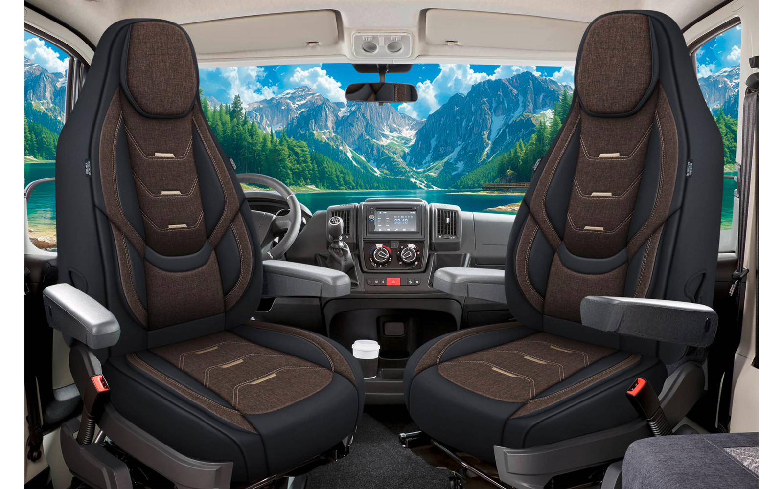 Fahrzeuginnenraum mit zwei Vordersitzen, Lenkrad, Armaturenbrett und durch die Windschutzscheibe sichtbaren Bergen, See und Bäumen