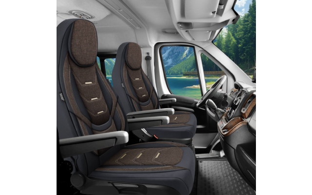 Innenraum eines Fahrzeugs mit zwei braunen Vordersitzen, Armlehnen, Lenkrad, Armaturenbrett und Blick auf See und Berge durch die Windschutzscheibe