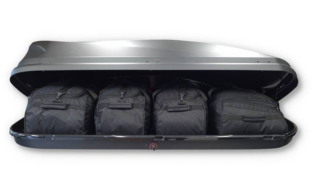 Geöffneter Dachkoffer mit vier schwarzen Reisetaschen nebeneinander