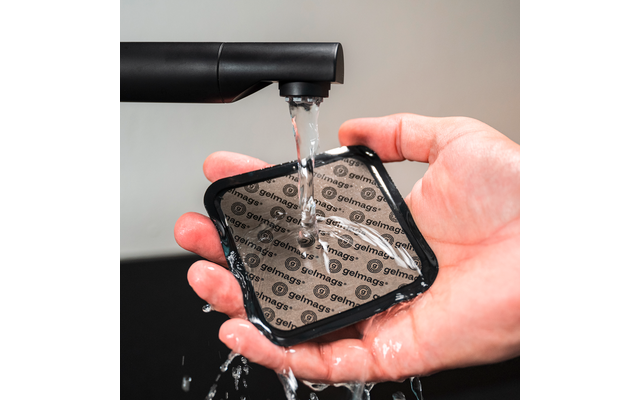 Hand houdt een vierkant zwart pad met herhaalde tekst "gelmags" onder stromend water uit een kraan
