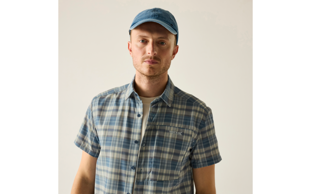Mann mit blauer Baseballkappe und blau kariertem Kurzarmhemd vor hellem Hintergrund, schaut in die Kamera