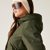 Frau mit Sonnenbrille, beiger Mütze und grünem Wintermantel mit Kapuze