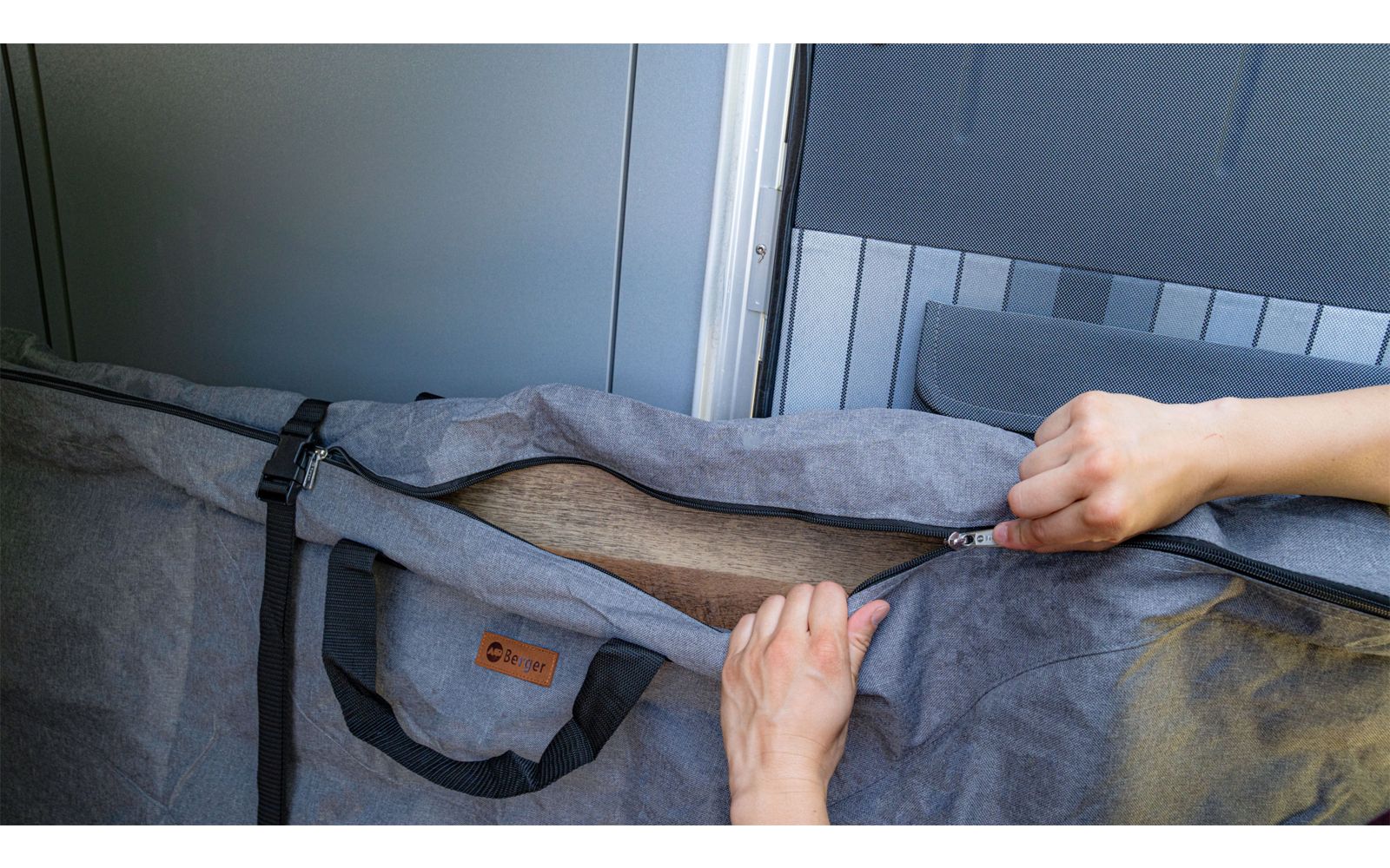 Hands opening a zipper on a gray fabric bag