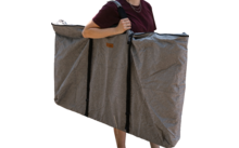 Person trägt zwei große graue Taschen vor einem weißen Wohnmobil