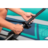 Hände stecken ein Paddel in eine Halterung auf einem türkis-blauen aufblasbaren Stand-up-Paddle-Board mit Muster