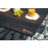 Plateau de table foncé avec raisins verts, verre de jus d'orange sur un dessous de verre blanc à franges, logo 'Berger' à l'angle, pieds métalliques et sol rayé visibles
