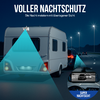 Wohnwagen auf einer nachts befahrenen Straße, dahinter ein Auto mit roten Rücklichtern, Straßenlampen am Straßenrand, türkisfarbene konische Lichtflächen über und neben den Fahrzeugen, kreisförmige Einblendung mit schwarz-weißem Kamerabild und dem Te
