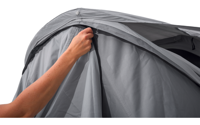 Hand zieht Reißverschluss an gebogenem grauen Stoff