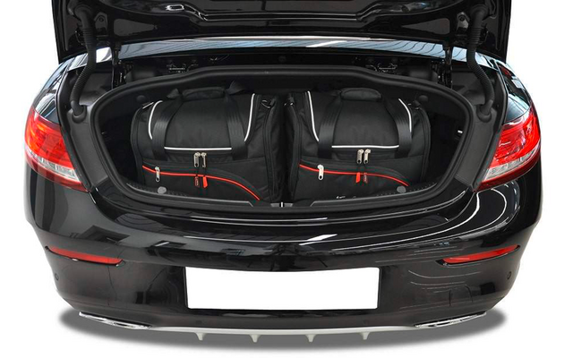 Coffre ouvert d'une voiture noire avec deux sacs de voyage noirs et une plaque d'immatriculation blanche