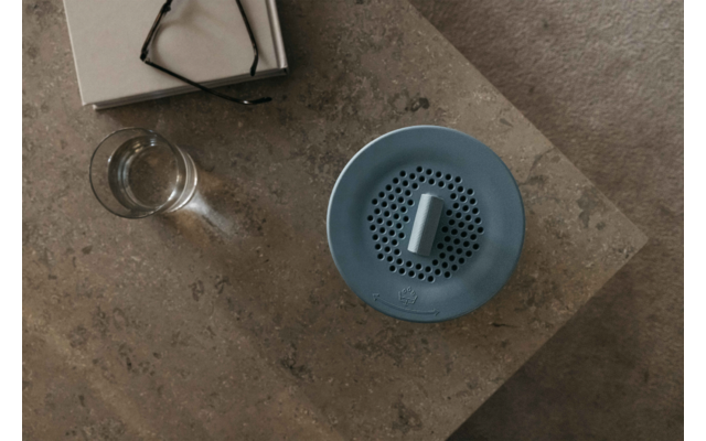 Blaue runde Luftbefeuchter auf einem Holztisch neben einem Glas Wasser