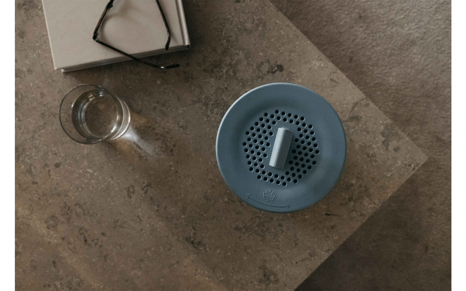 Blaue runde Luftbefeuchter auf einem Holztisch neben einem Glas Wasser
