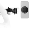 Black round adapter on the back of a smartphone next to a black vent clip with a mounting pin