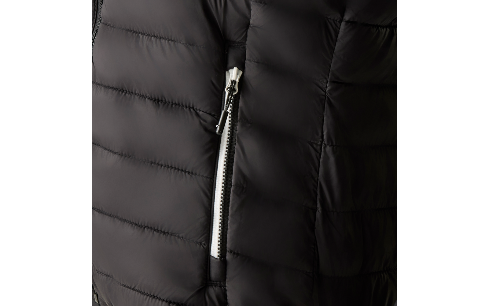 Nahaufnahme eines schwarzen, gesteppten Jackenstoffs mit horizontalen Nähten und einer silbernen Reißverschlusstasche