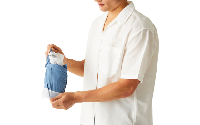 Personne en chemise blanche à manches courtes tenant un vêtement bleu et blanc plié