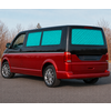 Red van, blue quilted window covers, parked on a road; leafless trees and sky in the background