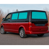 Red van, blue quilted window covers, parked on a road; leafless trees and sky in the background