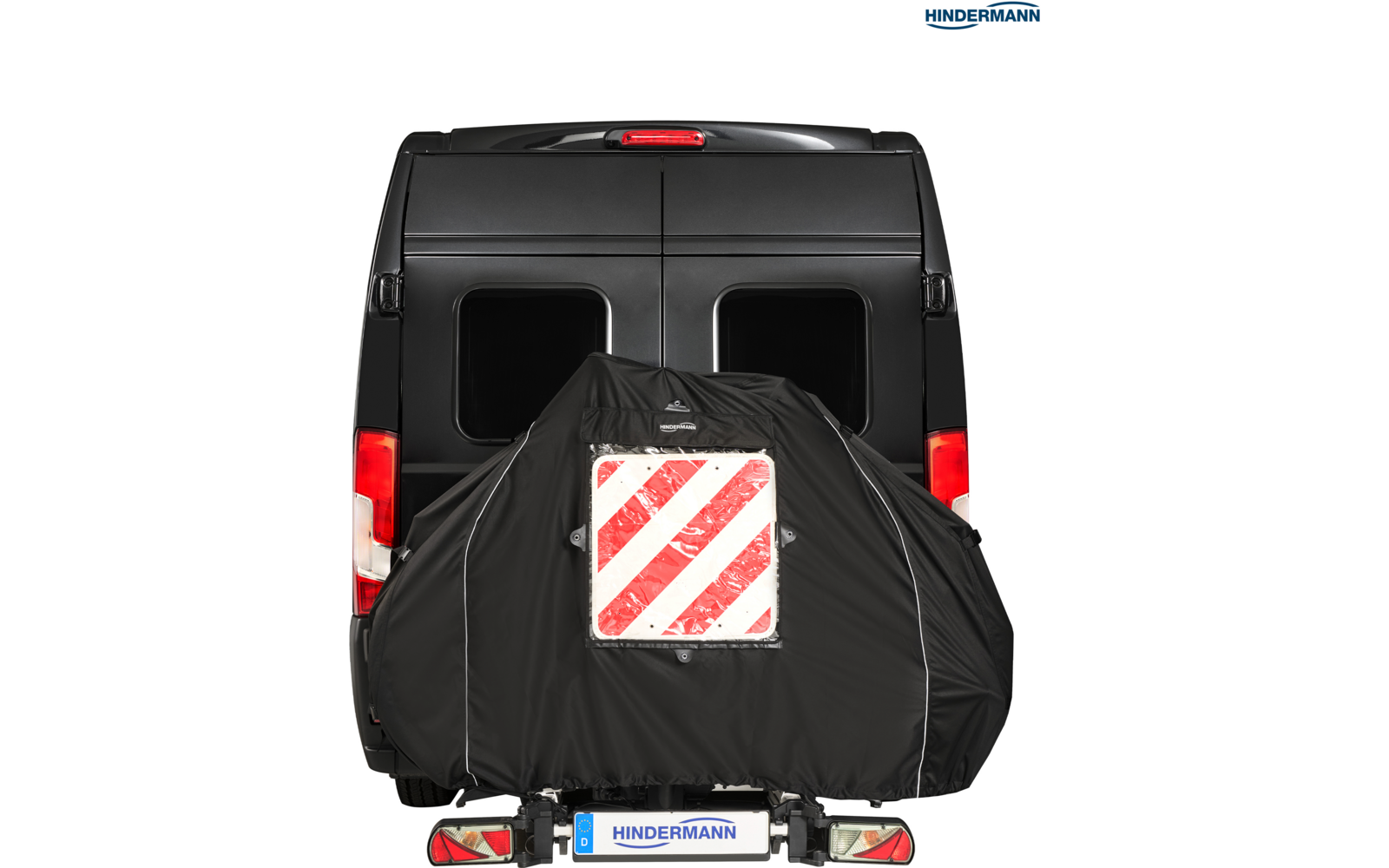 Heckansicht eines schwarzen Transporters mit zwei rechteckigen Heckfenstern; an der Rückseite ein schwarzer Überzug mit einem weißen Schild und roten diagonalen Streifen; Rücklichter und Kennzeichen 'HINDERMANN' sichtbar