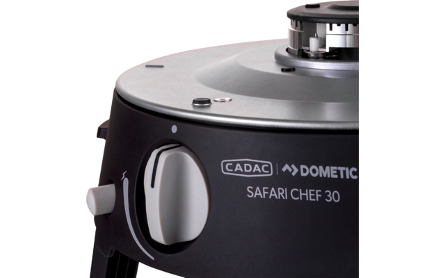 Gros plan d'un appareil rond avec une plaque supérieure argentée, une ouverture de brûleur visible, un boîtier noir, un bouton de commande blanc et l'inscription 'CADAC DOMETIC SAFARI CHEF 30'
