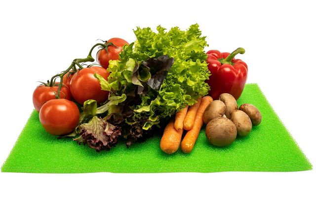 Pomodori sul ramo, cespo di lattuga, peperone rosso, carote e funghi marroni su una superficie verde