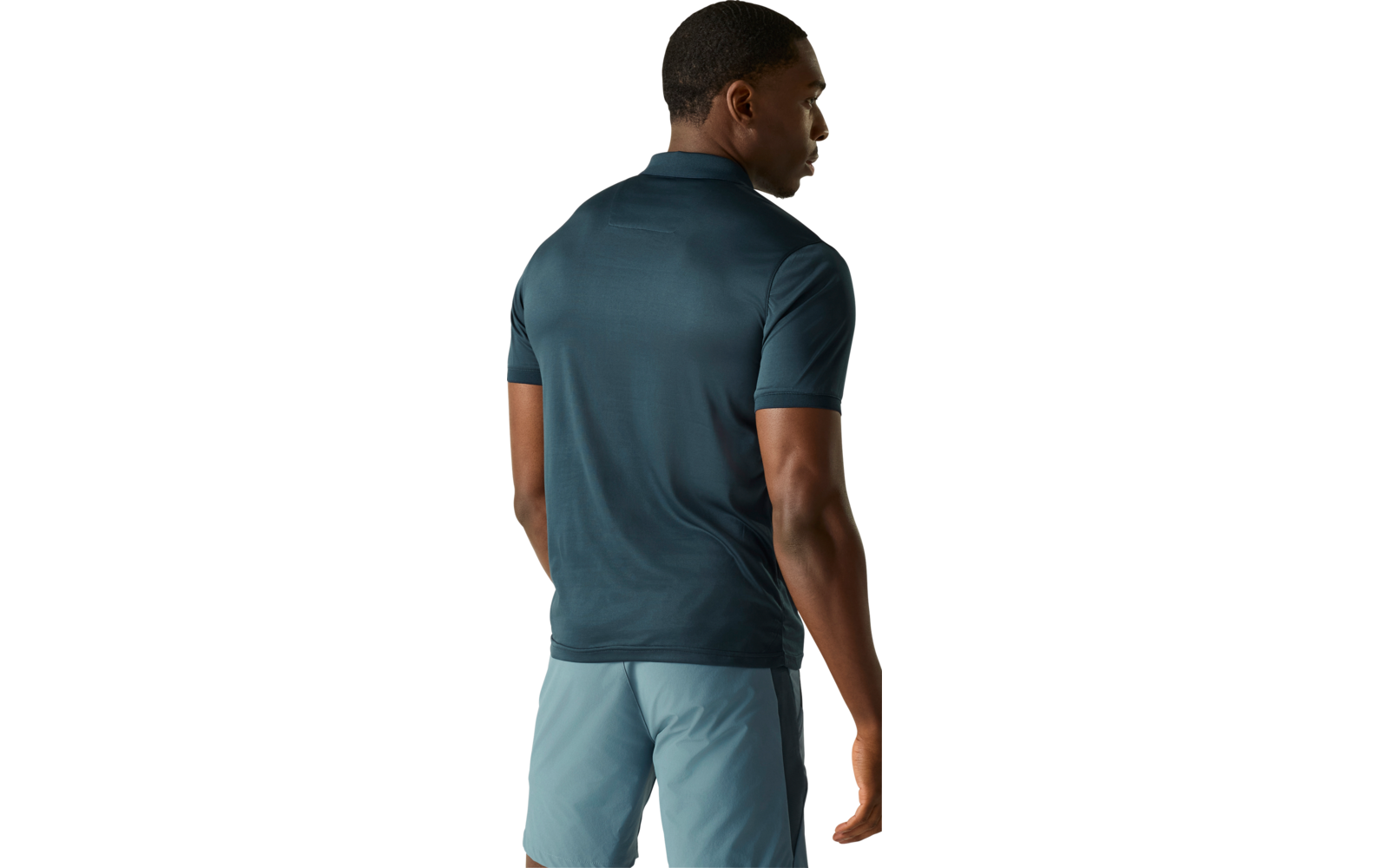 Person von hinten trägt dunkeltürkises Poloshirt und hellblaue Shorts, Kopf leicht nach rechts gedreht