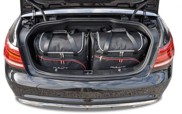 Coffre ouvert d'une voiture noire avec deux sacs de voyage noirs côte à côte