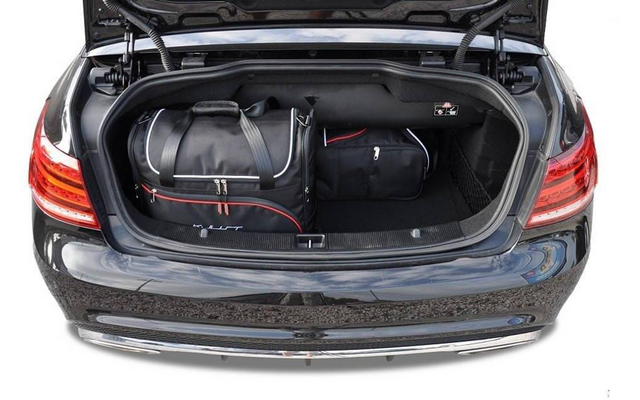 Coffre ouvert d'une voiture noire contenant un grand sac de voyage noir et un sac noir plus petit