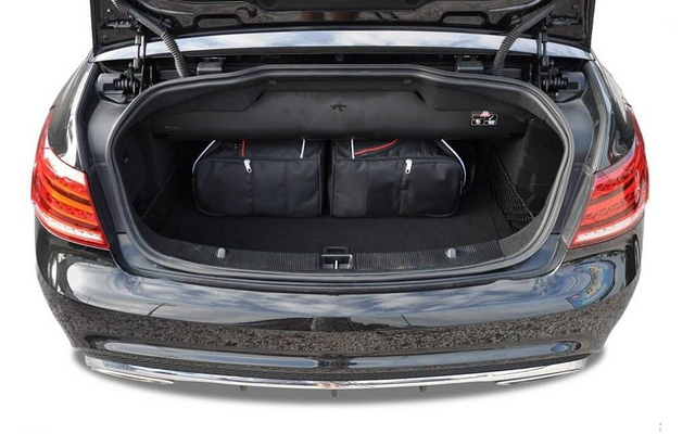 Coffre ouvert d'une voiture noire contenant trois sacs de voyage noirs avec des détails rouges