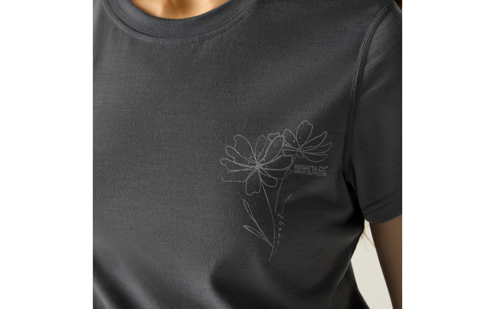 Oberkörper einer Person in dunklem T‑Shirt mit weißer Linien‑Blumenzeichnung und kleinem Schriftzug links auf der Brust