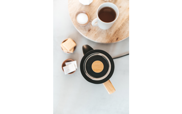 Taza de café, cubos de azúcar y una bandeja sobre una mesa de madera