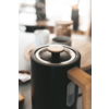 Molinillo de café negro con granos de café en una habitación luminosa