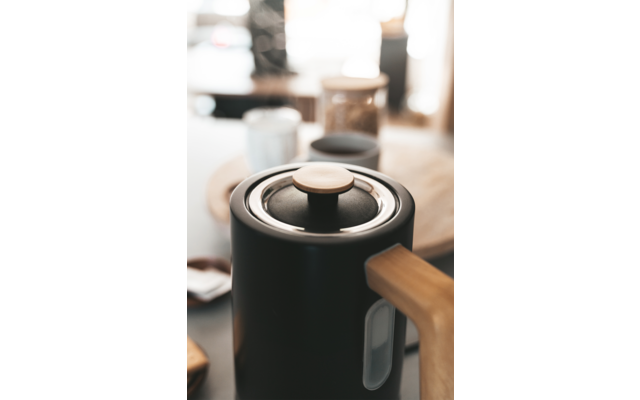 Molinillo de café negro con granos de café en una habitación luminosa