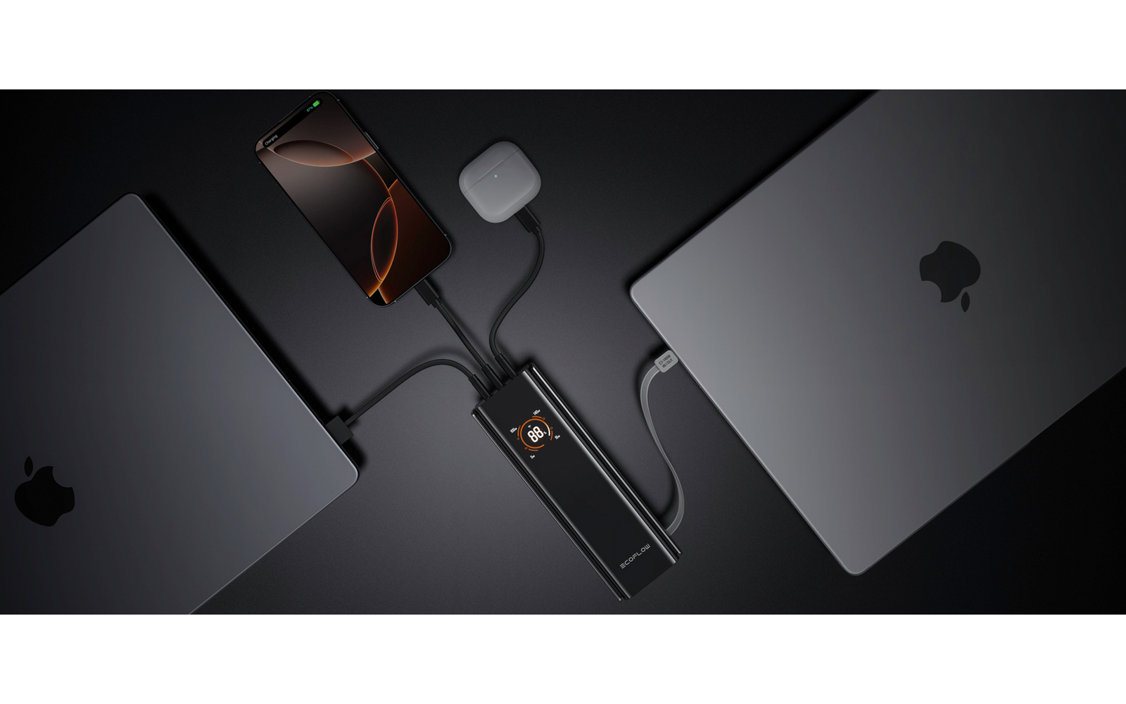 Zwei silberne Laptops mit Apfel-Logo, dazwischen eine schwarze Brille und ein schwarzes Handy auf dunkelgrauem Hintergrund