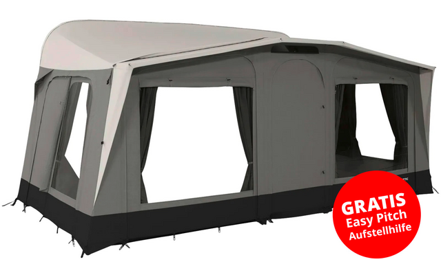 Large gray camping awning with multiple rectangular windows, dark base strip, curtains at the windows, curved roof, guy lines and ground pegs; red round sticker at lower right with white text