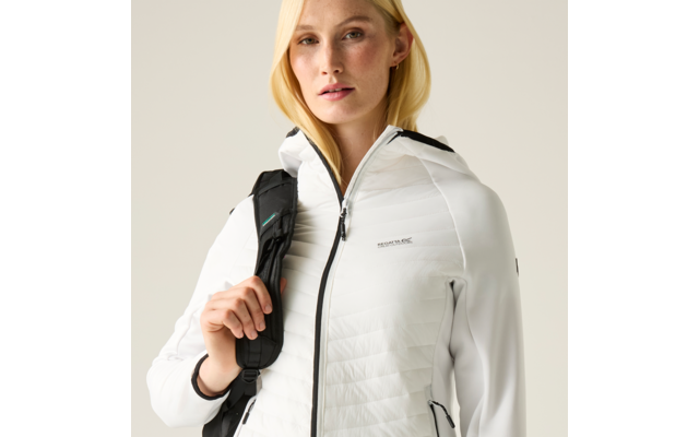 Person mit blonden Haaren trägt weiße gesteppte Jacke mit Kapuze und Rucksackträger über einer Schulter, heller Hintergrund