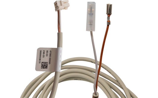 Aufgewickeltes weißes Kabel mit drei unterschiedlichen Enden: weißer Kunststoffstecker, transparenter Steckverbinder und offener Metallkontakt an einem dünnen braunen Draht; am Kabel ein Etikett mit Barcode