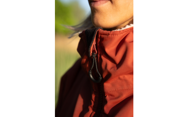 Nahaufnahme von Mund, Kinn und Hals; rote Jacke mit Reißverschluss und schwarzem Kordelzug; weißer Rüschenkragen; unscharfer grüner Hintergrund; Sonnenschein auf der Haut