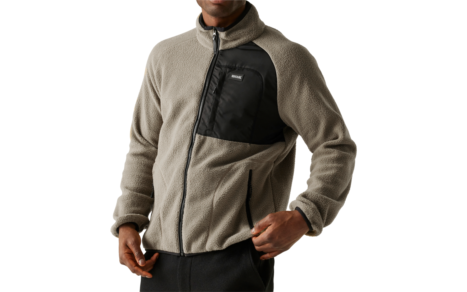 Ein Mann trägt eine graue Fleecejacke mit schwarzer Brusttasche und eine schwarze Mütze