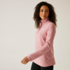 Frau mit lockigem Haar trägt einen rosa Pullover und blickt zur Seite