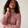 Frau mit lockigem Haar trägt einen rosa Pullover und schaut nach rechts oben