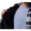 Person zeigt das Innere einer schwarz-weiß karierten Jacke, trägt ein hellblaues T-Shirt