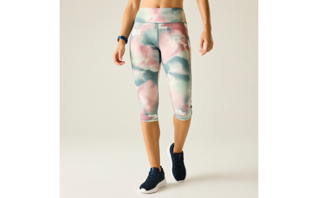 Lower body of a person from waist to feet wearing pastel cloud-pattern capri leggings, navy athletic shoes with white soles, and a fitness band on the wrist
