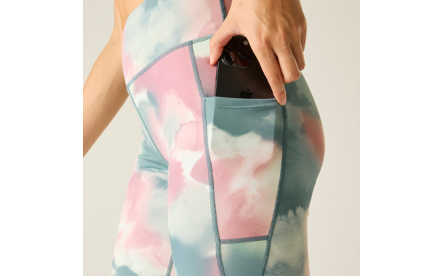 Hand placing a smartphone into the side pocket of pastel-colored leggings