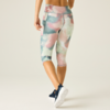 Person seen from behind wearing pastel watercolor capri leggings and navy sneakers on a light background