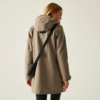 Frau mit langem blonden Haar trägt eine beige Jacke mit Kapuze und eine schwarze Umhängetasche, von hinten fotografiert