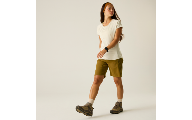 Persona con camiseta blanca, pantalones cortos verde oliva, botas de senderismo, calcetines claros, una cinta en la cabeza y un reloj inteligente sobre fondo claro