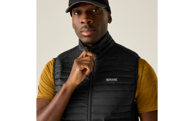 Person mit schwarzer Baseballkappe, schwarzer gesteppter Weste mit Regatta-Logo und gelbem T-Shirt, zieht am Reißverschluss