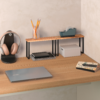 Holztisch mit geschlossenem Laptop, kleinem Holzregal mit Glas mit Bleistiften, Klebebandabroller, weißer Aufbewahrungsbox, Kopfhörer auf Ständer und zwei Bücher