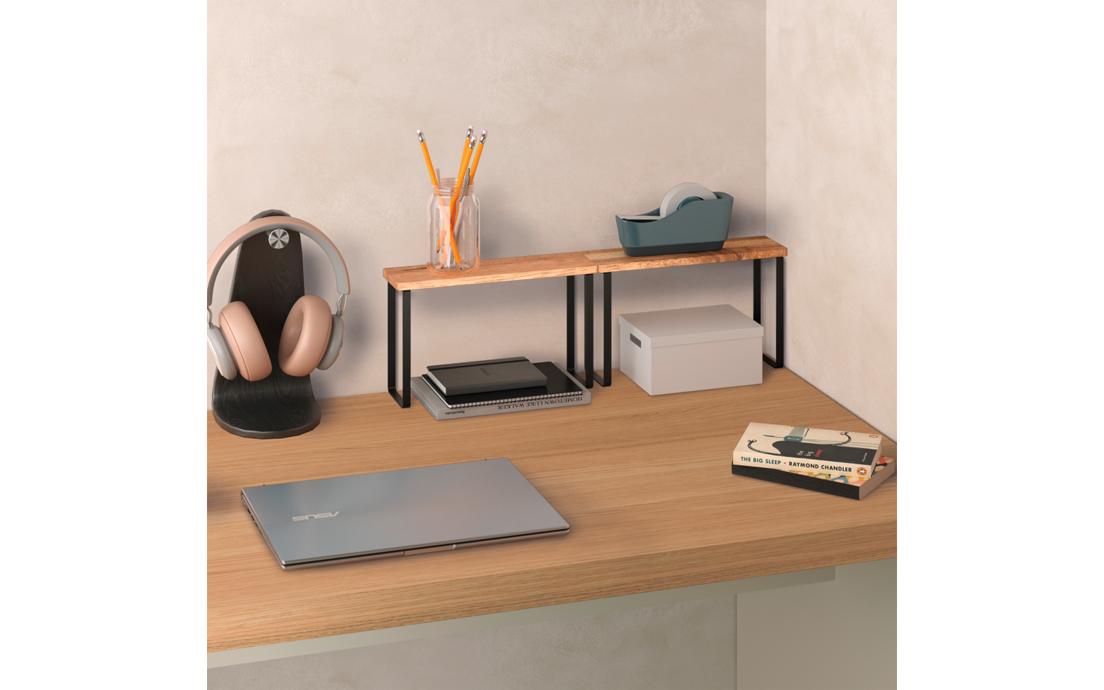 Holztisch mit geschlossenem Laptop, kleinem Holzregal mit Glas mit Bleistiften, Klebebandabroller, weißer Aufbewahrungsbox, Kopfhörer auf Ständer und zwei Bücher