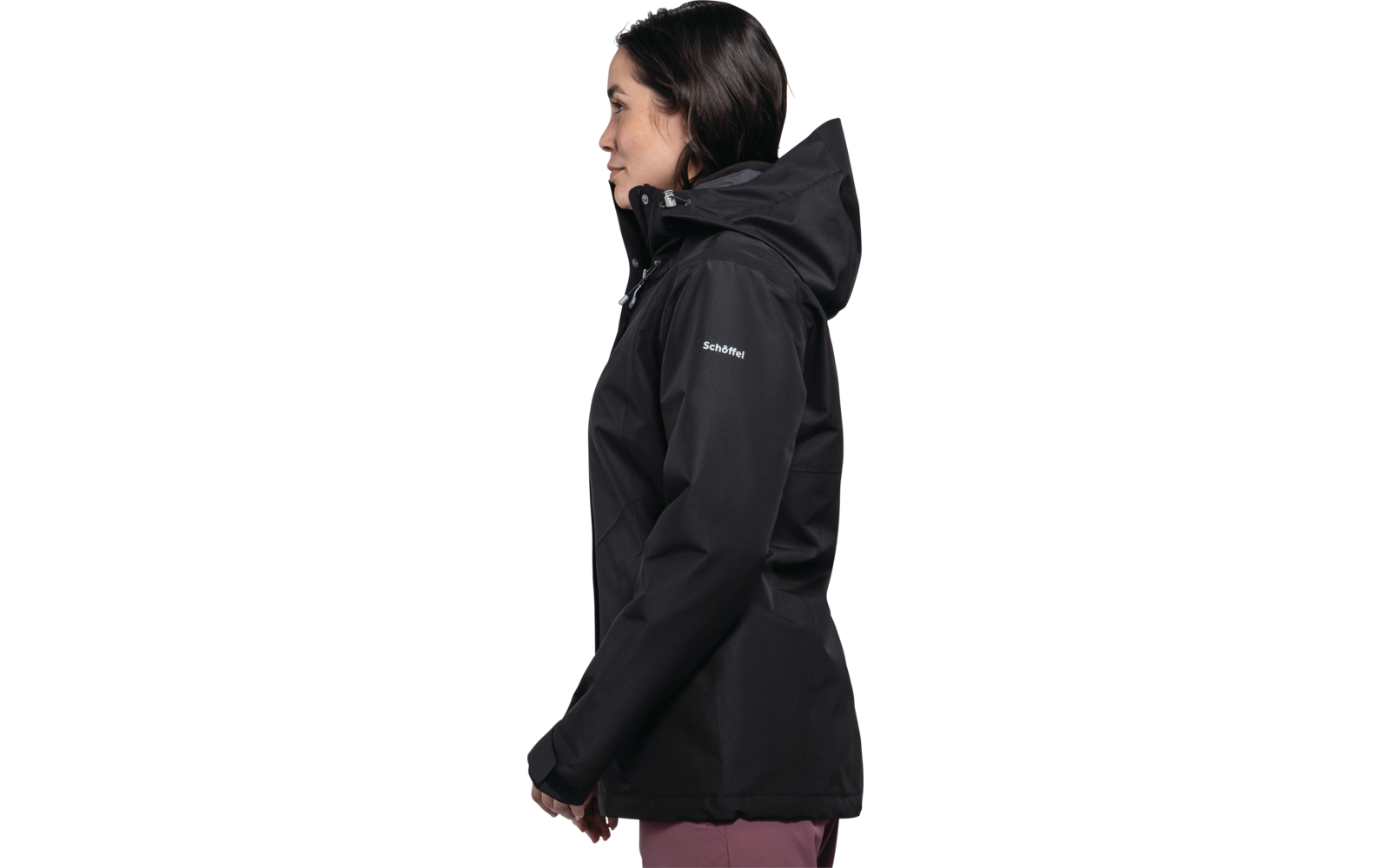 Seitenansicht einer Frau mit dunklen Haaren, die eine schwarze Jacke mit aufgesetzter Kapuze trägt; weißes Logo auf dem linken Ärmel; weißer Hintergrund