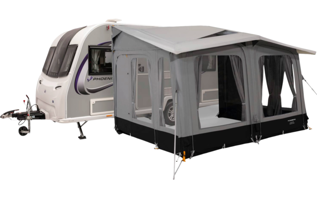 White caravan with attached gray awning/annex, visible windows with curtains, guy lines and support poles; trailer hitch visible at front